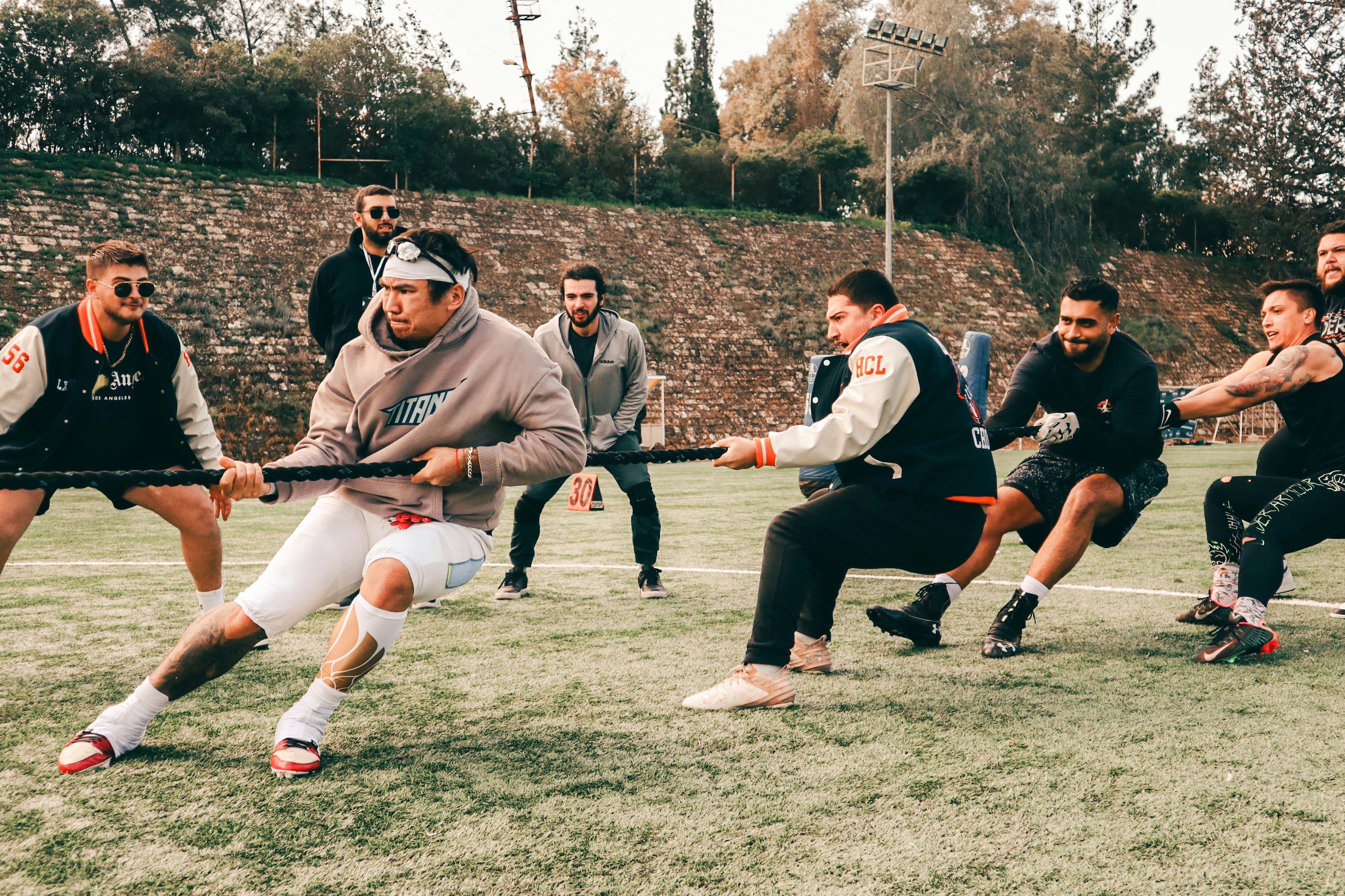 Lower-body view of a group tug-of-war on a grass field.
